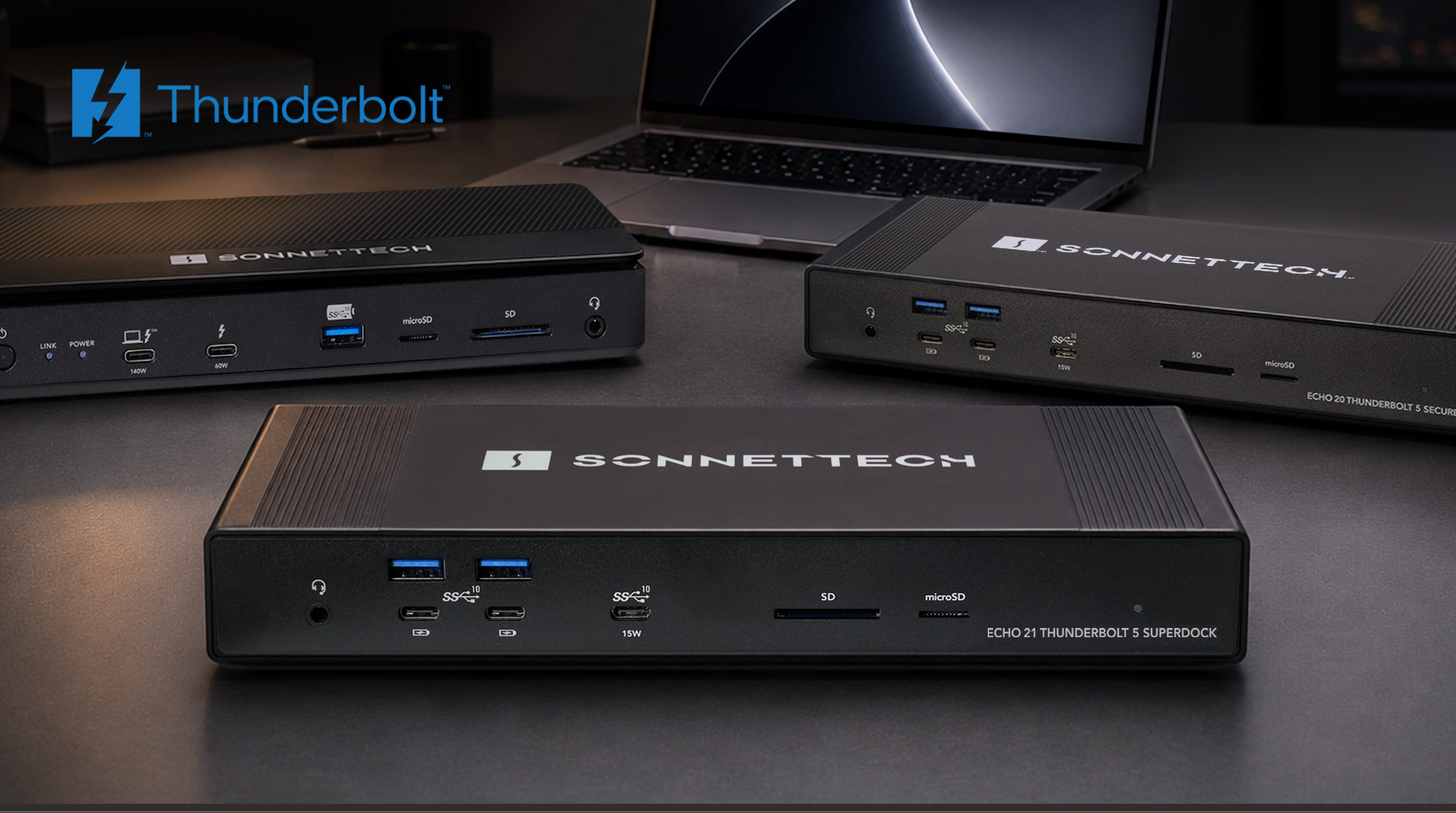 Group of Thunderbolt docks with MacBook Pro on desk.